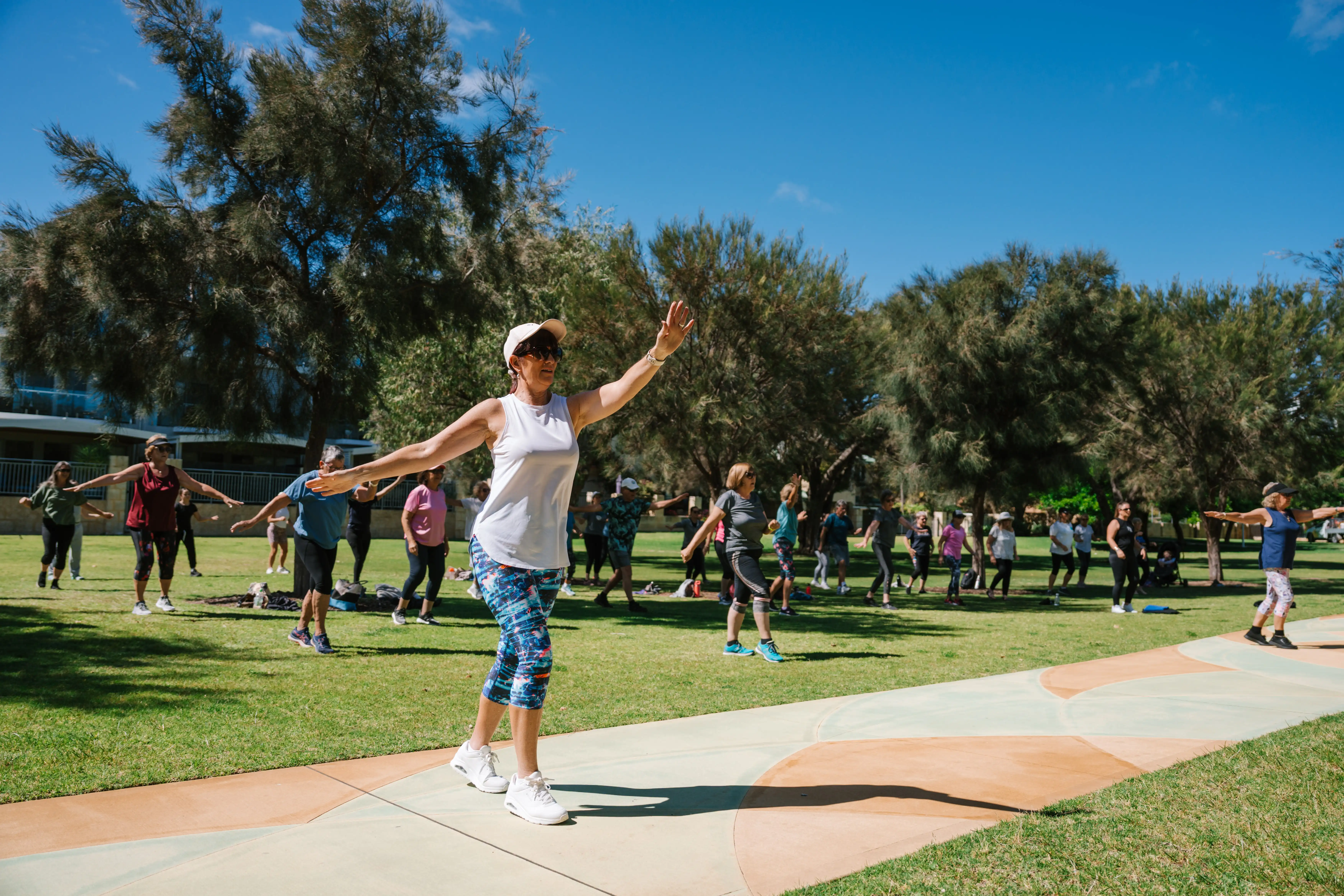 Exercise instructor leading exercise group in park.