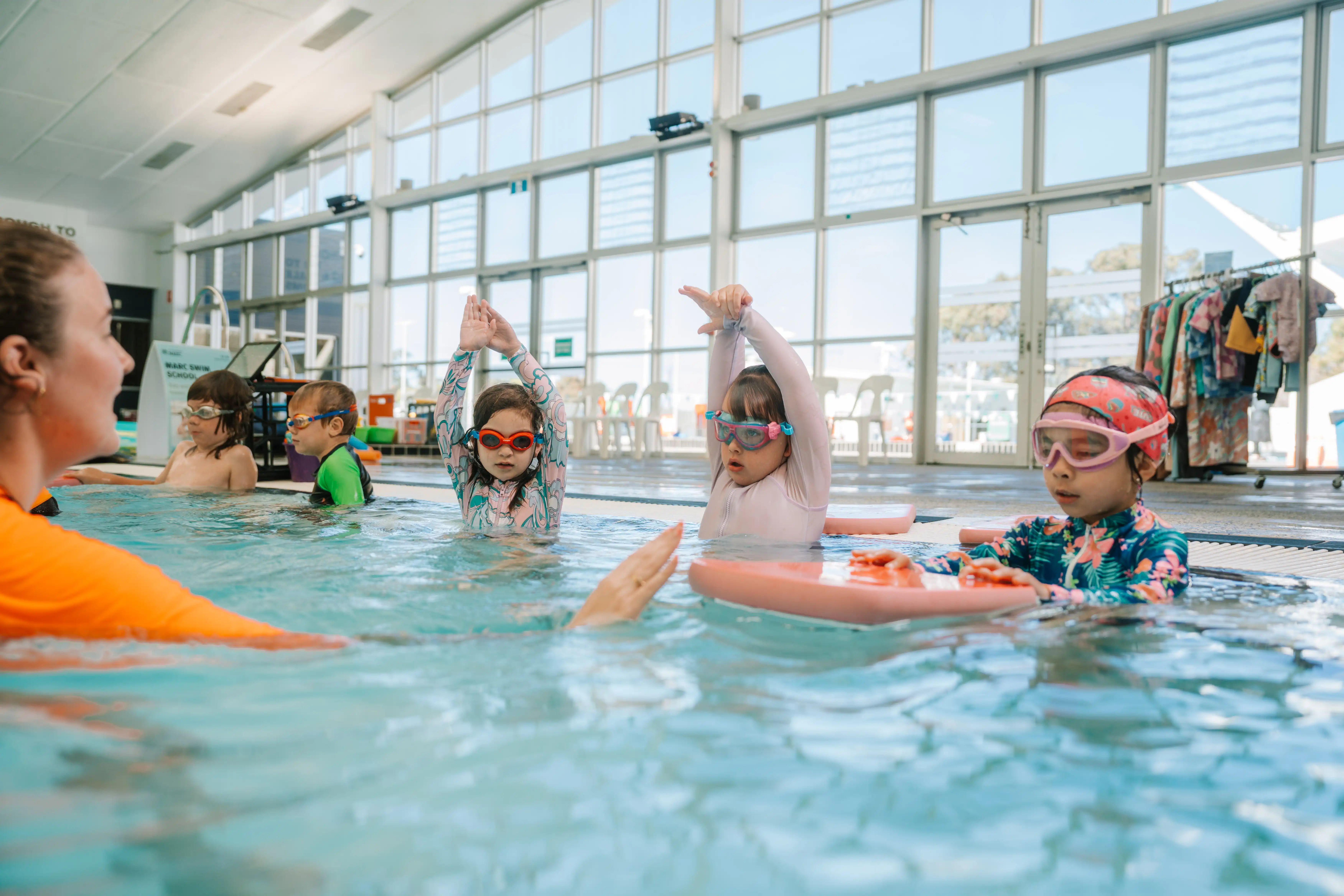Multiple children in pool with swim teacher.
