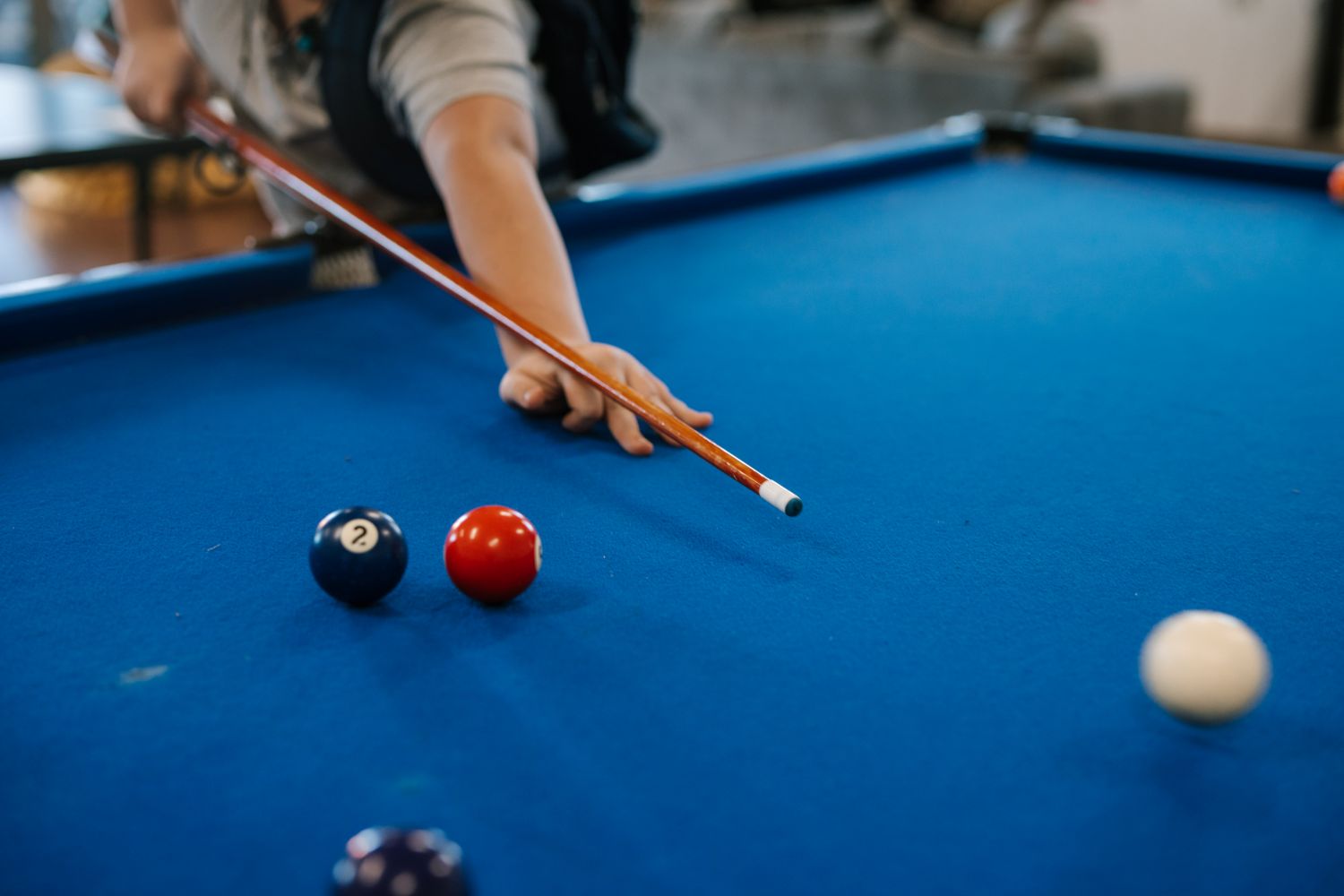 A person lines up a shot on a blue pool table at the BDYC, with billiard balls positioned on the table.