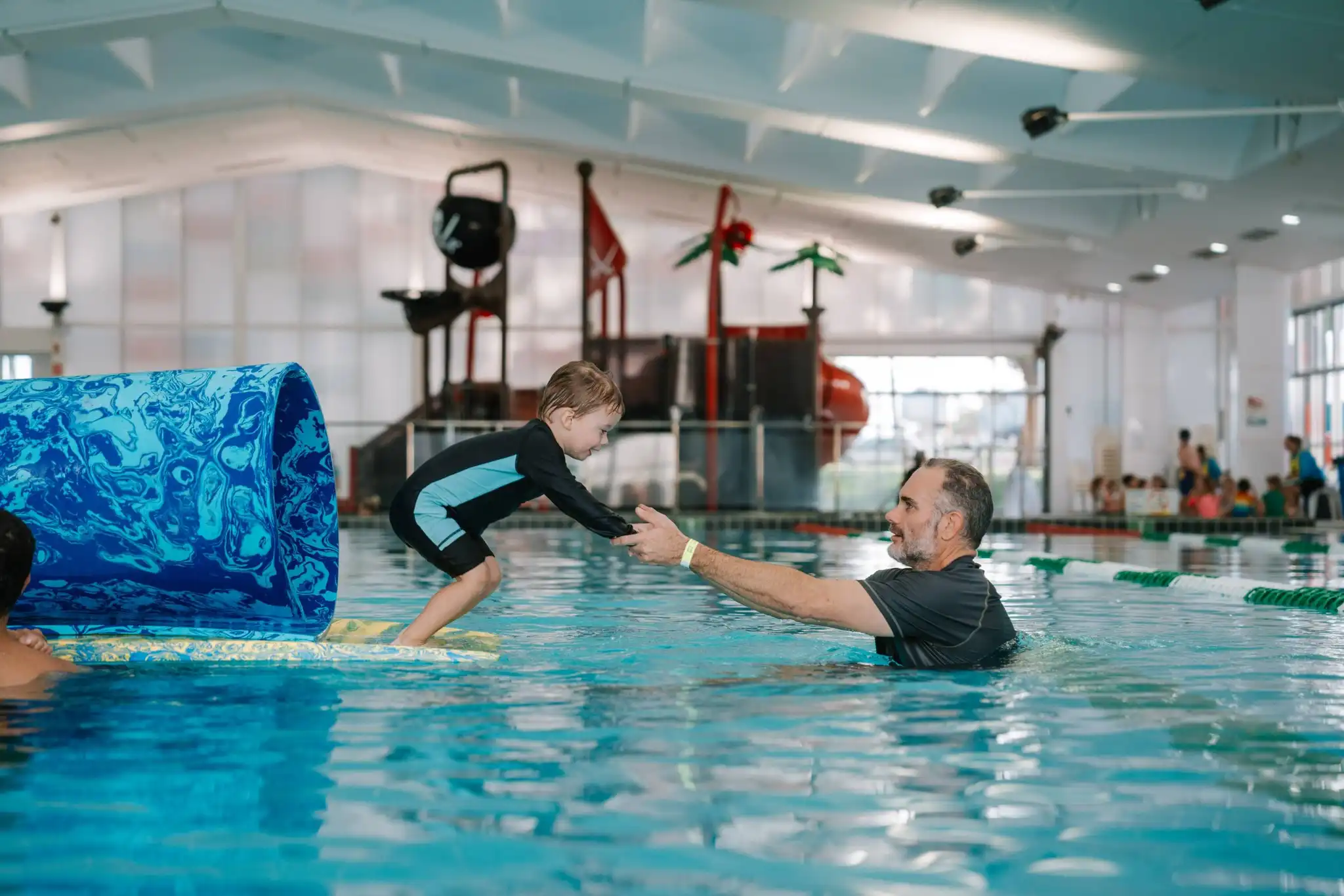Adult and child in a pool wearing Watch Around Water wristbands.